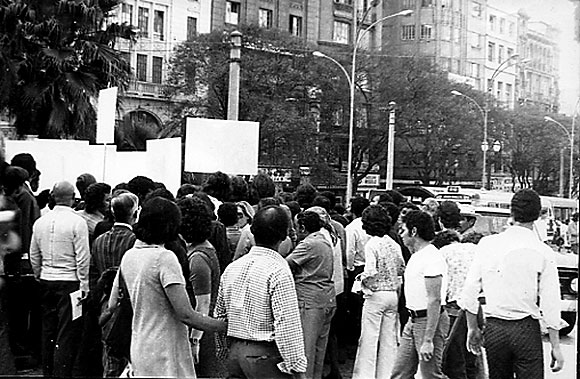 7. O Branco invade a cidade. Esta ao de rua que conduzir  priso de Fred Forest pela polcia militar da junta ser um golpe sobre o acontecimento mais importante desta XII Bienal de So Paulo. Ela consistir no deslocamento do artista por So Paulo, acompanhado por aproximadamente quinze pessoas carregando cartazes brancos. A provocao era ainda mais evidente, pois o regime da poca proibia o agrupamento de mais de trs pessoas no espao urbano. Os jornalistas da grande imprensa diria brasileira, cmplices objetivos de Fred Forest, tinham anunciado esta ao na vspera, sob o ttulo de Higiene da arte: o branco invade a cidade. De acordo com um itinerrio distribudo, o grupo conduzido por Forest circulou pelo centro de So Paulo passando por todos os lugares simblicos e histricos. Transcorridos quinze minutos, uma multido considervel reuniu-se progressivamente a este cortejo inslito e a circulao foi bloqueada em diferentes pontos da cidade. Este priplo que se desenvolveu por volta de duas horas terminou com a irrupo da polcia, a apreenso dos cartazes e a captura do artista, levado ao DOPS. 